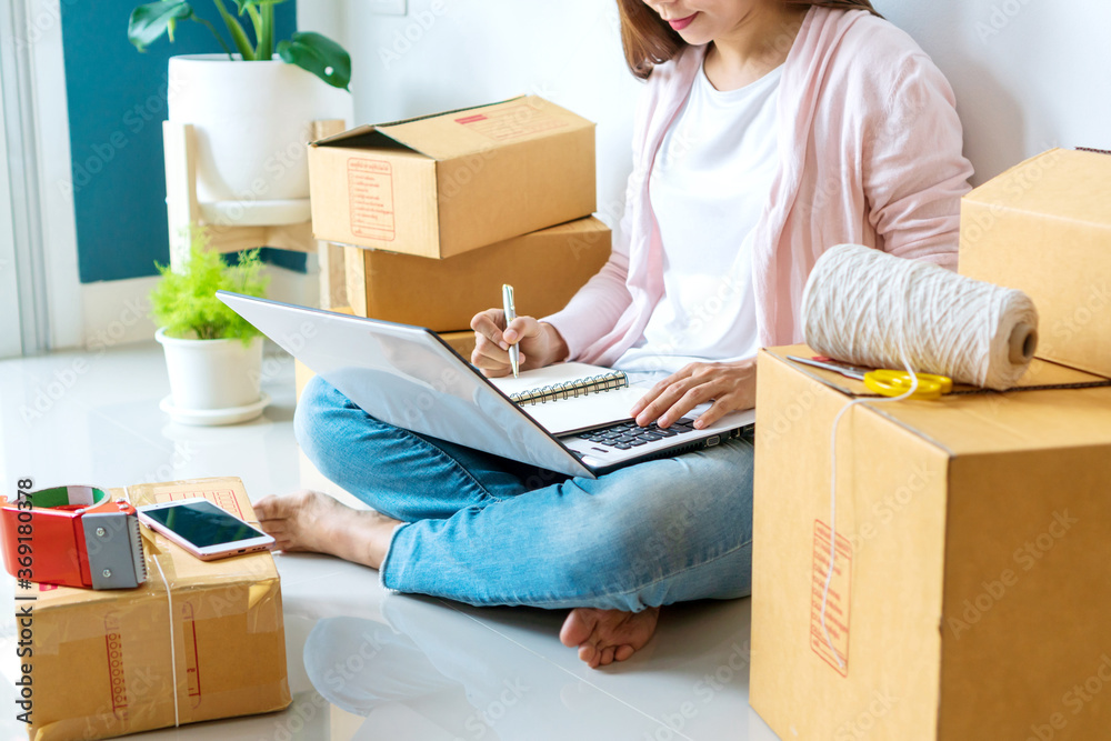 Asian beautiful woman entrepreneur checking order on her laptop and writing to memorandum book. Online selling, Business and Technology , new normal concept. Asian beautiful woman entrepreneur checking order on her laptop and writing to memorandum book. Online selling, Business and Technology , new normal concept.