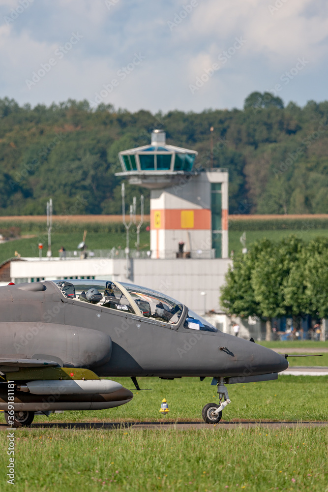 Fototapeta premium Air Force jet trainer aircraft taxiing at an airbase with the air traffic control tower behind.