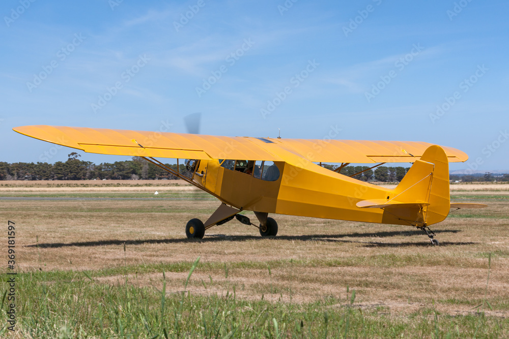 Bright Yellow light aircraft on the grass of a small airfield. Bright Yellow light aircraft on the grass of a small airfield.