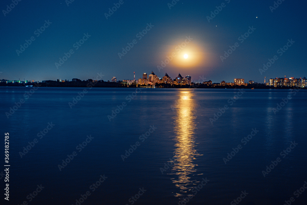 night view of the city and the wide river from the embankment. the city lights up beautifully. High quality photo