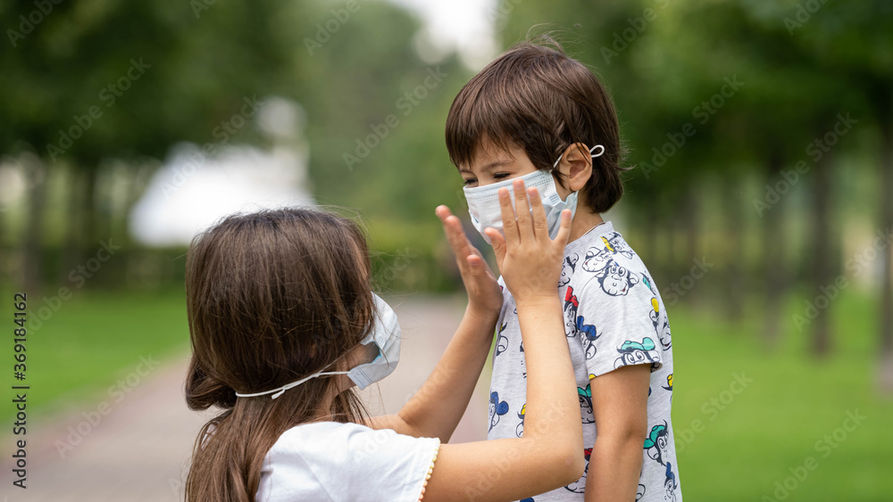 Obraz premium a young girl helps her brother to wear a face mask from the coronavirus covid19