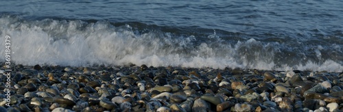 Sea pebble shore with a splash of foam wave.