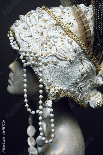 Head of mannequin in creative white headwear with feathers and pearls