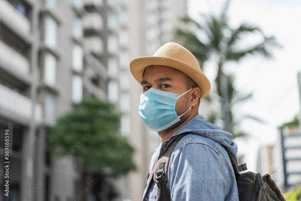 Young asian backpacker traveling in urban city wearing face mask for protect virus safety travel.