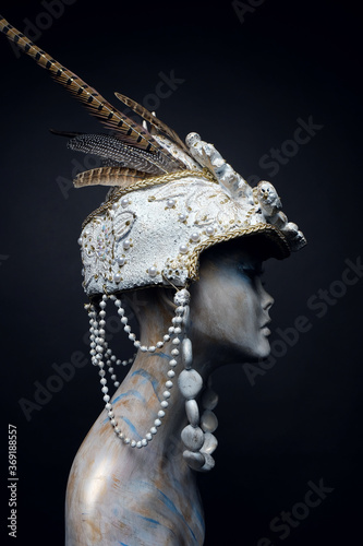 Head of mannequin in creative white headwear with feathers and pearls