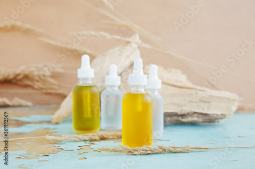 Bottles of essential oils or fluid collagen on blue-yellow pastel background. Beauty concept.