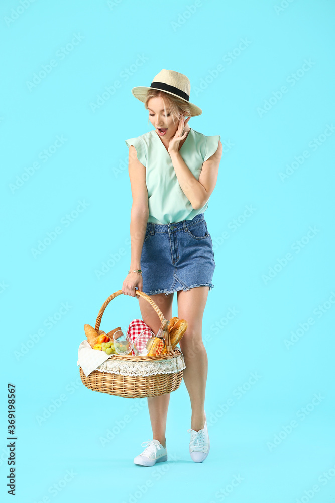 Surprised woman with food for picnic in basket on color background Surprised woman with food for picnic in basket on color background