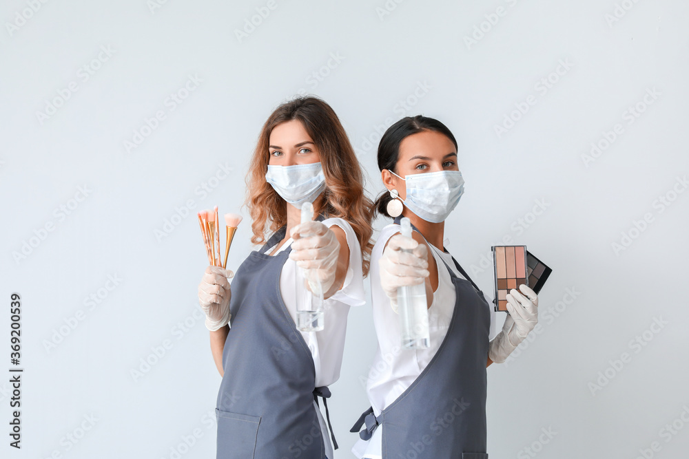 Female makeup artists wearing medical masks on light background. Coronavirus epidemic Female makeup artists wearing medical masks on light background. Coronavirus epidemic