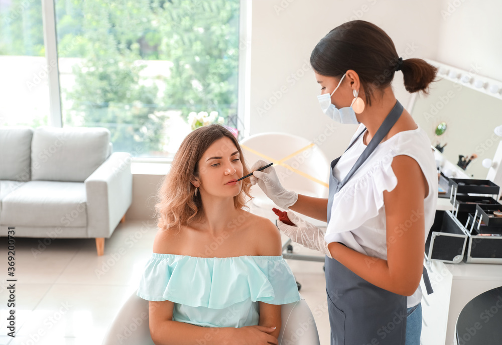 Female makeup artist working with client in salon during coronavirus