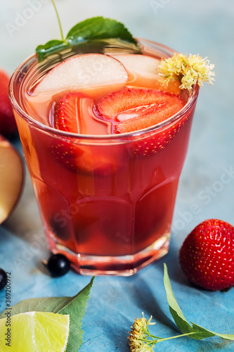 Red cocktail in glass with strawberry  apple and lime