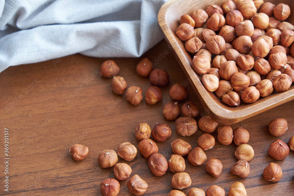 Fototapeta premium Hazelnut kernels and whole hazelnuts on old brown table, selective focus.