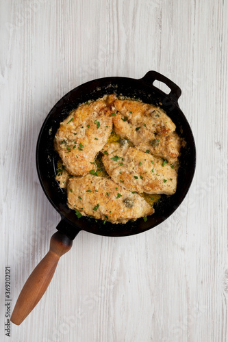 Homemade Italian Chicken Piccata in a cast iron pan, top view. Overhead, from above, flat lay.