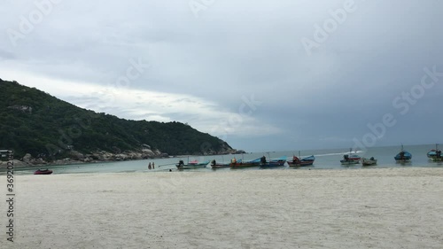 Quiet beach in Thailand, Koh Phangan, with long tails and jet-ski, watersports. Cloudy day. Static shot. photo