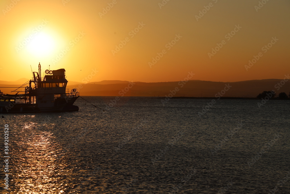 Fishing boat silhouette with yellow and orange sunset colors in the background