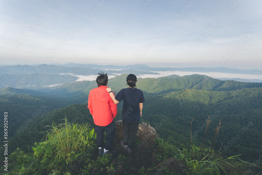 rear of happy couple love stand on top mountain looking view at morning light. soft focus.