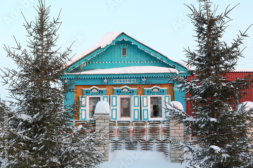 Wooden rural house with richly decorated traditional national carved windows in russian village (Ulyanovsk region, Russia). Russian folk style in wooden architecture. Building facade. Snow winter photo