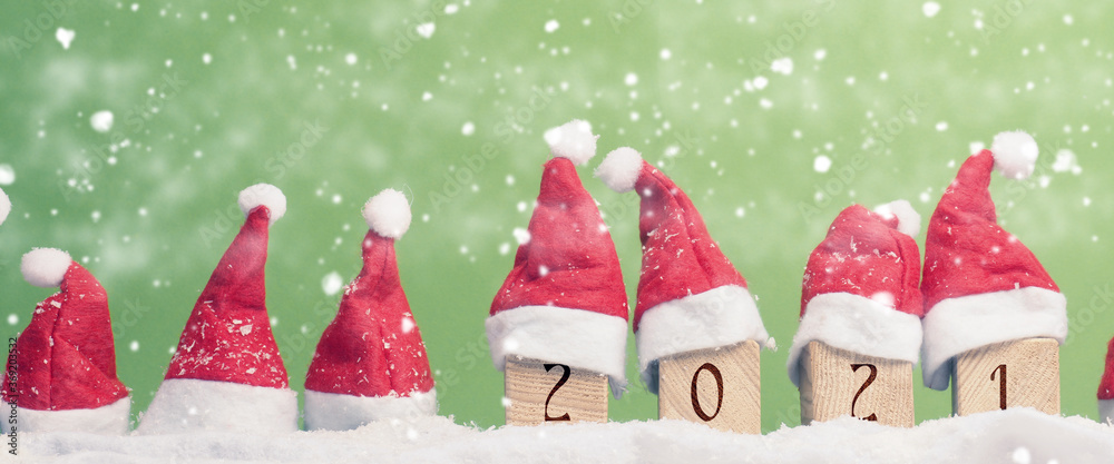 Many hats of Santa in a row with snow, New Year 2021 on wooden blocks, Christmas background, panoramic view - obrazy, fototapety, plakaty 