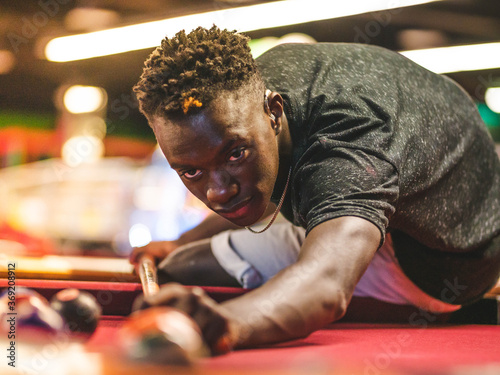 Shallow focus shot of a young black male in a billiards playroom