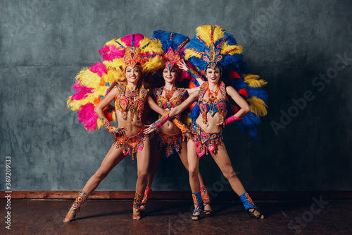 Three Woman in brazilian samba carnival costume with colorful feathers plumage. photo