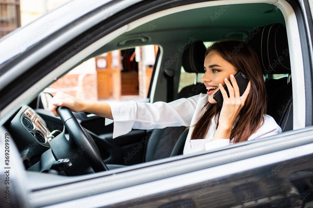 Young woman making a phone call while driving a car to work. Young woman making a phone call while driving a car to work.