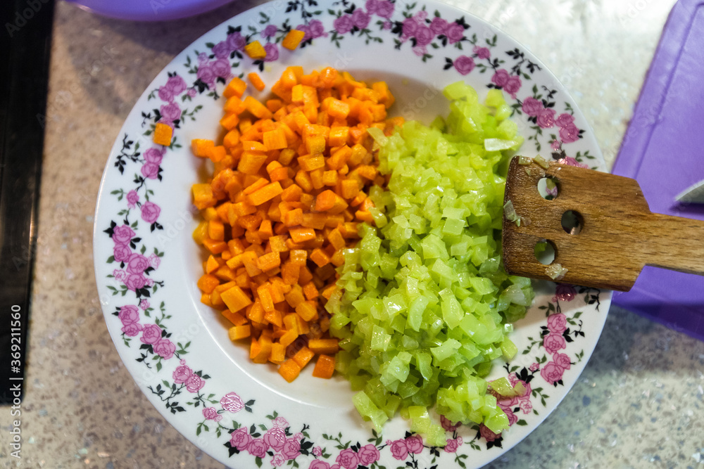 Plate with chopped frying carrots and green pepers as ingredients for vegetable stew.Top view. Spatula, cutting board, bowl.