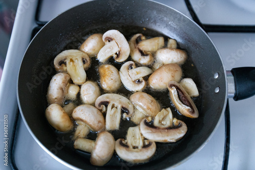 Obraz na płótnie Sauteed in olive oil small champignons with chopped garlic. Mushroom cooking in frying pan top view. Homemade food. w salonie