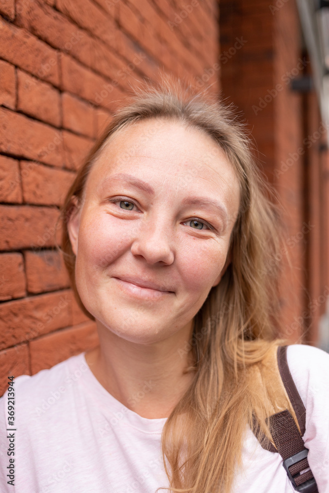 a beautiful smiling girl in a white t-shirt and jeans poses on the streets of the city. she has long hair and no makeup. the architecture of the old city is a backdrop around it. High quality photo a beautiful smiling girl in a white t-shirt and jeans poses on the streets of the city. she has long hair and no makeup. the architecture of the old city is a backdrop around it. High quality photo