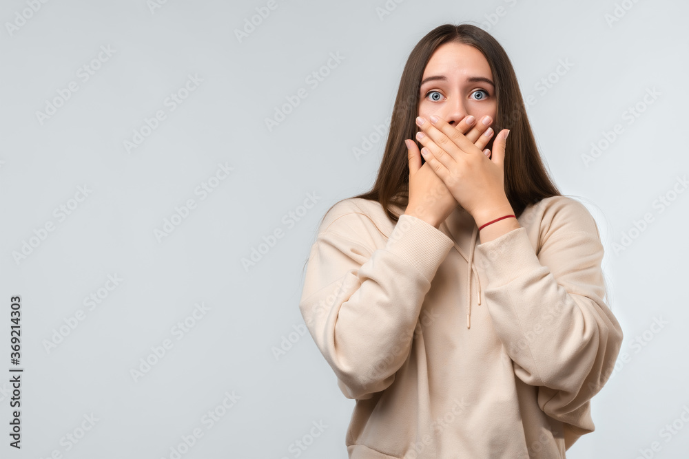 Shocked young woman covering mouth with hands on white background. Keep silence concept Shocked young woman covering mouth with hands on white background. Keep silence concept