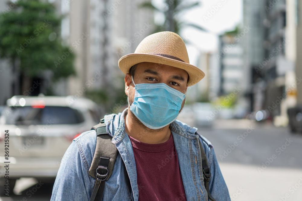 Young asian backpacker traveling in urban city wearing face mask for protect virus safety travel.