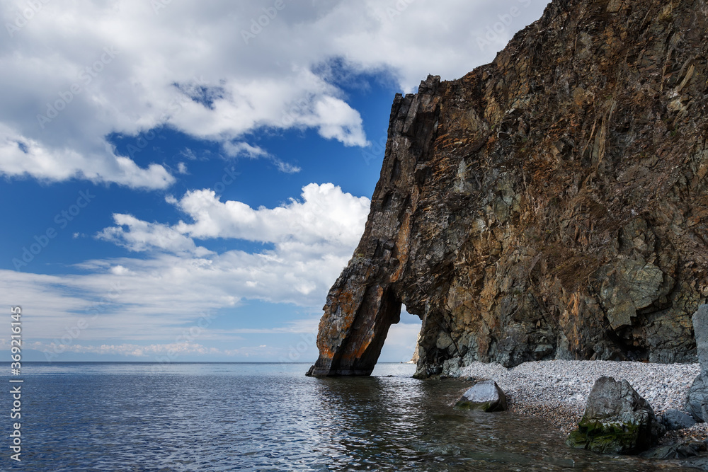 Big cliff looks like elephant proboscis at Baikal lake shore in summer with blue sky and clouds