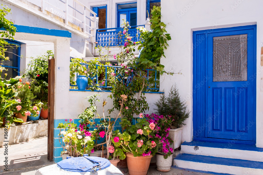 Φωτογραφία Plaka Town on Milos Island - picturesque narrow stone street with traditional greek whitewashed walls, blue doors, window shuttes and blooming colorful flowers, Greece