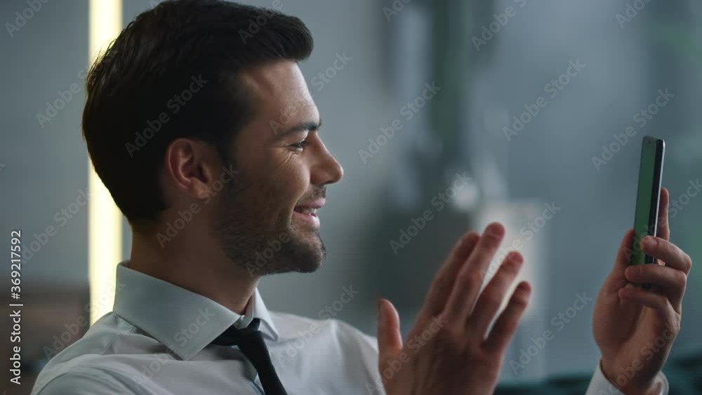 Businessman video chatting online on smartphone. Man waving hand at phone camera Businessman video chatting online on smartphone. Man waving hand at phone camera