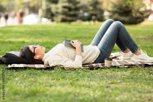 Girl lying in warm summer grass, listening ro music © Prostock-studio