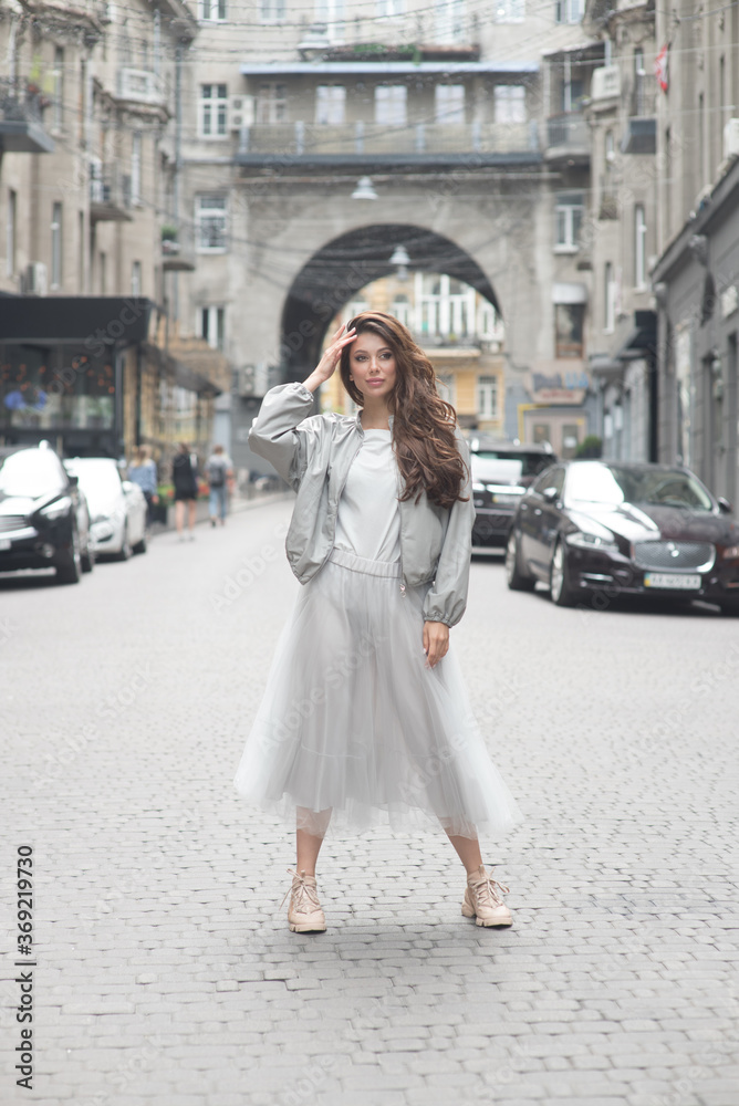 Fototapeta premium Young girl poses in a middle of a street. Soft selective focus. Fashion. Streetstyle.