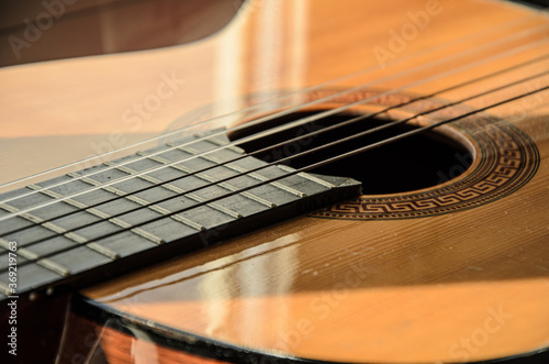 Close-up of guitar strings in sunlight. Guitar fretboard part, acoustic six-string wooden guitar, stringed musical instrument.