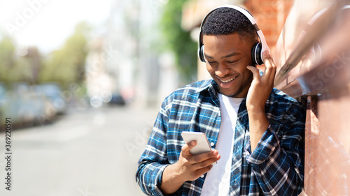 Foto Portrait of guy listening to music leaning against the wall