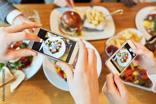 Hands with smartphones take pictures of food