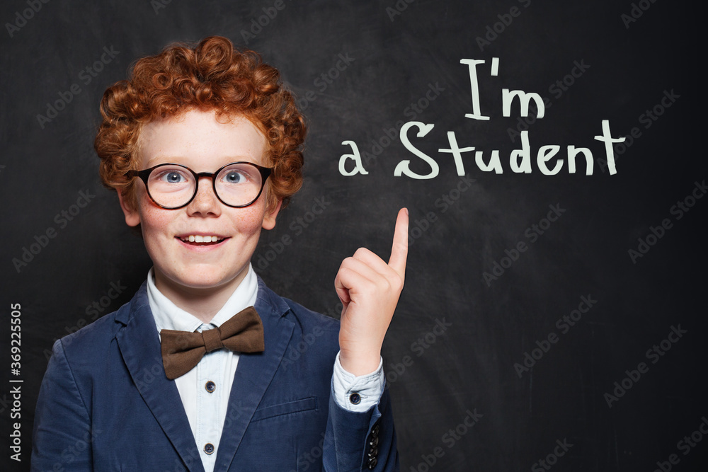 Happy prodigy child student on blackboard background portrait