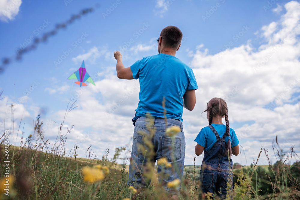 Happy childhood and summertime. Kid and father playing with a kite, outdoor