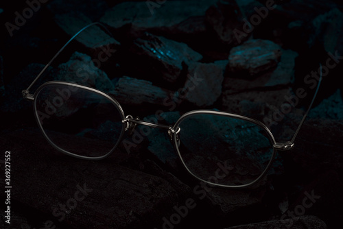 silberne Brille auf schwarzer Holzkohle mit blauem Licht