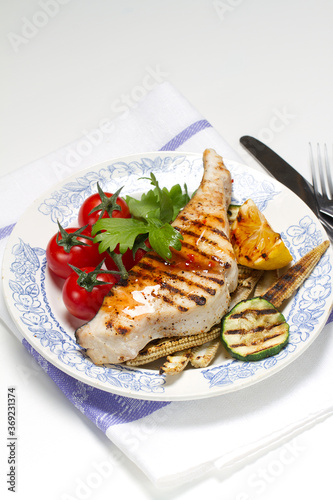 Grilled swordfish steak, young corn, zucchini, lemon, cherry tomatoes, chili sauce and celery leaf