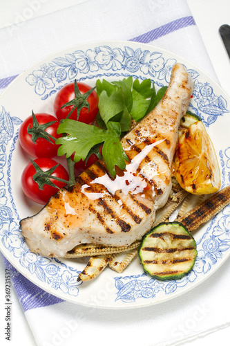 Foto Grilled swordfish steak, young corn, zucchini, lemon, cherry tomatoes, chili sau