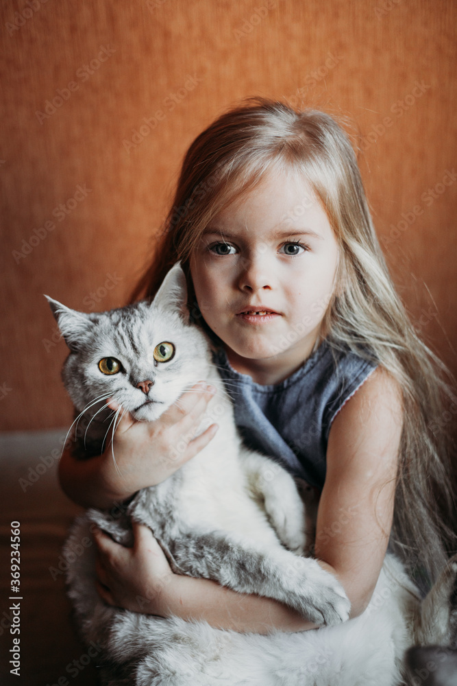 a girl with blond hair holds a cat , a pet, and a house