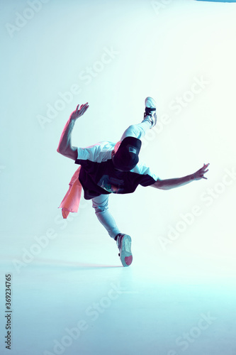 Young guy breakdancer performs trick in jump dancing in studio in neon light. Break dance lessons. Dance school poster