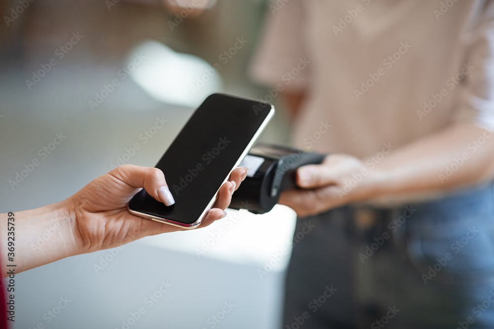 Wireless Payment. Close up female hand using smartphone, paying contactless at cafe Wireless Payment. Close up female hand using smartphone, paying contactless at cafe