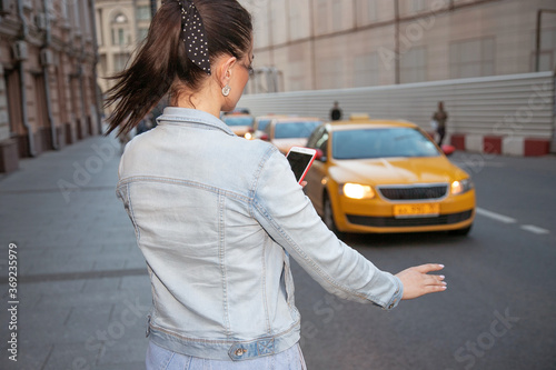 young woman waiting for a taxi on the street with a phone in her hand © Нарине Нахшкарян