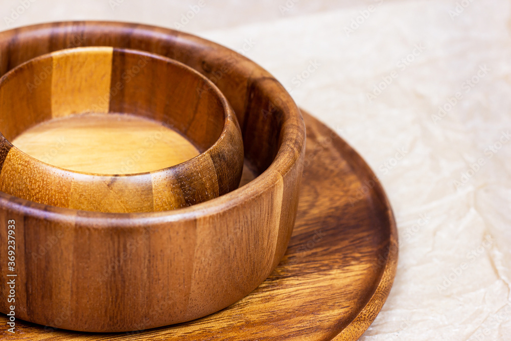 Traditional brown round wooden eco bowls with spoon on light table background in the kitchen. Traditional brown round wooden eco bowls with spoon on light table background in the kitchen.