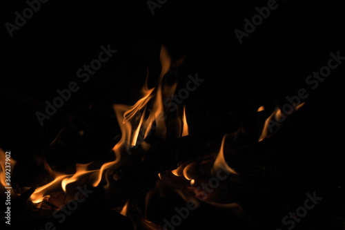 Burning wood at night. Campfire at touristic camp at nature in mountains. Flame amd fire sparks on dark abstract background. Cooking barbecue outdoor. Hellish fire element. Fuel, power and energy