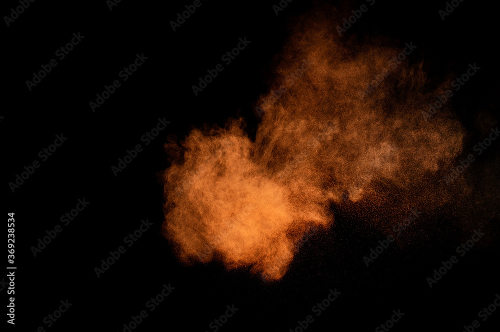 Fototapeta premium Orange powder explosion on black background. Colored powder cloud. Colorful dust explode. Paint Holi.