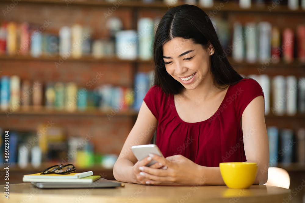 Smiling Asian Girl Messaging On Smartphone During Coffee Break In City Cafe Smiling Asian Girl Messaging On Smartphone During Coffee Break In City Cafe